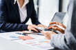 © Phushutter - Two female business professionals in suits sit at desk, engaged in strategic discussion. They analyze financial planning, risk management, corporate growth while reviewing reports and market trends.