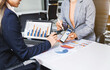 © Phushutter - Two female business professionals in suits sit at desk, engaged in strategic discussion. They analyze financial planning, risk management, corporate growth while reviewing reports and market trends.