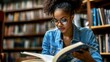 © Ludmila Zabaranilova - Attractive female student in stylish denim apparel reading information from knowledge textbook and analyzing plan for course work, dark skinned hipster girl learning and preparing to university exams