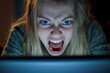 © Janja - Young girl shouting angrily at laptop screen in the dark