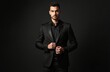 © Vadym - Elegant young handsome man in black suit posing on dark studio background. Serious fashionable businessman executive portrait. Stylish confident guy wears jacket and shirt. Male beauty and fashion.