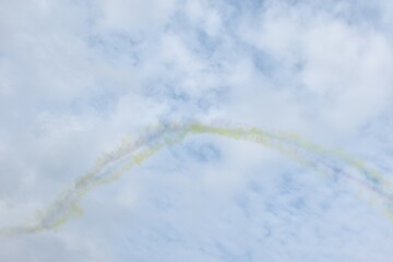 Wall Mural - colorful vapor condensation trail from plane spreading in cloud on bright sky in sunny day