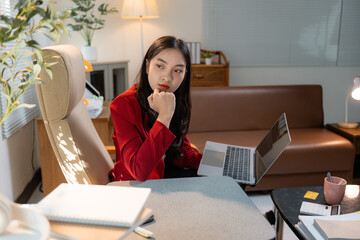 Aufkleber - Young asian businesswoman thinking and working with laptop in home office