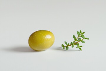 Poster - Studio shot of single green olive with vibrant thyme sprig on a clean white surface for food photography