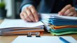 © Rizvan - Businessman hands looking through unfinished stacks of paper files on office desk for report papers, piles of documents archived with clips on table, Document is written, drawn, presented.