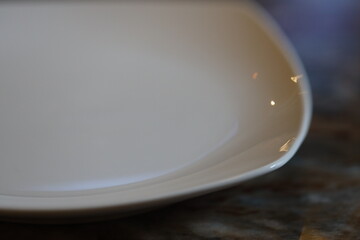Poster - A close-up shot of a clean white plate on a table, perfect for food or still life photography.