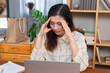 © Rakchanok - Young Asian stress women in casual get headache using laptop working at home in living room, thoughtful freelance businesswomen small business architect entrepreneur concentrated planning on computer