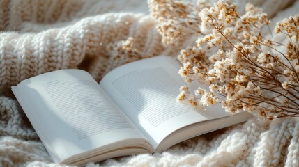 Aufkleber - An open book rests on a plush knitted blanket, surrounded by delicate dried flowers. Soft afternoon light creates a peaceful atmosphere, perfect for reading and relaxation