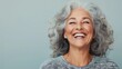 © Nataliia_Trushchenko - Woman with gray hair is smiling and laughing. She is wearing a gray sweater and has a big smile on her face