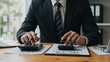 © Qbertstudio - Caucasian businessman in suit using calculator and laptop at office desk analyzing financial reports and data