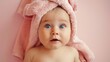 © night - A baby with big blue eyes looks up at the camera while wrapped in a towel.