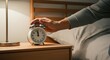 © Tati - Hand turning off alarm clock on bedside table