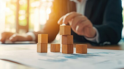 Poster - A businessperson stacks wooden blocks on a document, symbolizing strategy and growth in a professional environment.