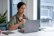 © MIND AND I - Businesswoman sitting at desk on couch in workplace or at home working on laptop and analyzing data on charts and graphs and writing on papers to make business plan and strategies for company,