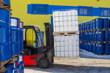 Poster - Plastic barrels are transported on forklift. Territories of chemical products warehouse. Forklift with IBC on pallets. Unloading petroleum near warehouse. Forklift near industrial building