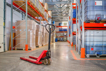 Poster - Warehouse distribution center. Logistic storage interior. Empty pallet jack between warehouse racks. Warehouse with IBC with containers. Logistics center inside hangar. Fulfillment center from inside
