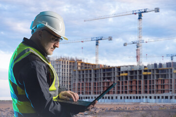 Poster - man builder holding laptop. heads architectural company. builder near multi-storey residential compl