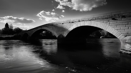 Poster - a black and white image of a bridge spanning a river, with dramatic shadows