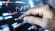 © Somporn Na Ubon - Close up of hand interacting with digital stock market display, showcasing financial data and trends