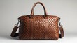 © Firadoaw - A meticulously crafted brown leather bag, its intricate weaving patterns hinting at artisanal skill, stood majestically against a crisp white backdrop, showcasing both its craftsmanship and timeless