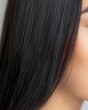 © Fokasu Art - Close-up of healthy, shiny black hair cascading over a woman?s shoulder, perfect alignment of hair strands, neutral solid backdrop