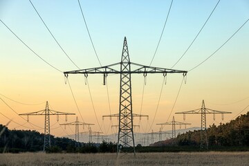 high voltage power lines over a field at sunset