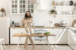 © fizkes - Healthy cooking and joyful dancing. Excited millennial woman happy homeowner housewife having fun in modern well equipped renovated kitchen dance move enjoy preparing delicious homemade vegetable food