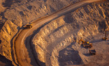 Banner industry, heavy industrial dump truck transports copper and gold ore in open pit mine, sunset