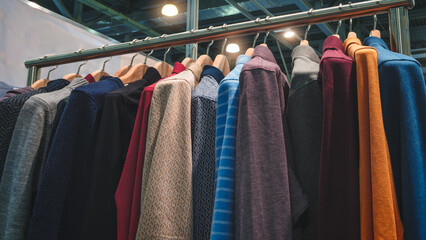 Poster - A rack of colorful shirts in a store. The shirts are arranged in a rainbow order, from light to dark. The display is eye-catching and inviting, drawing the attention of potential customers