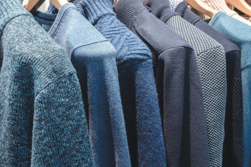 Poster - A rack of sweaters with a tag on the red one. The sweaters are of different colors and styles