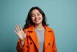 © starush - A cheerful young woman waves hello while wearing an orange coat