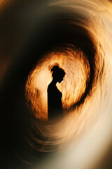 Poster - Silhouette of Contemplative Woman Against a Dynamic Swirl of Warm Golden Tones