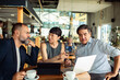© Marko Geber - Diverse business team collaborating in modern cafe