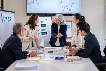 a group of people are sitting around a table with a whiteboard behind them