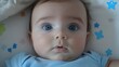 © imagineRbc - A baby with blue eyes is laying on a bed