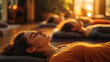 © Art of Ngu - Women lying on yoga mats in a meditation session, practicing Shavasana relaxation pose in a warm, softly lit studio with a peaceful atmosphere.