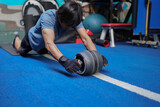 A man using ab wheel roller exercising in gym.