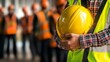 © santima - Worker holding yellow helmet at construction site.