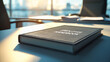 © Y.a.o.W - An Employee Handbook resting on a sleek office desk. The background is softly blurred, showing an office scene.