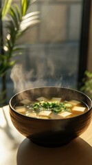 Poster - Close-up of steaming soup in a bowl garnished with green herbs on a sunny kitchen table