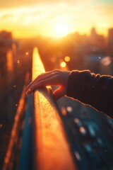 Poster - A person's hand grasping a railing as the sun sets behind, suggesting a moment of contemplation or reflection