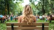 ©  Shomixer - A young woman sits on a bench, gazing at a lively park scene, capturing a moment of contemplation amidst nature, highlighting the connection between solitude and observation.