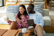 © NDABCREATIVITY - Young happy multiethnic couple having fun while using laptop, digital device at home