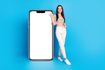 Poster - Full body portrait of nice young lady point finger empty space smart phone screen isolated on blue color background