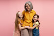 © Maria Vitkovska - Grandmother embracing granddaughters celebrating Easter on pink background