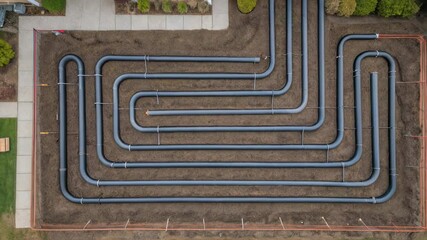 Poster - Construction workers are installing a geothermal system in a residential backyard, connecting pipes and trenches in a specific pattern to harness underground thermal energy