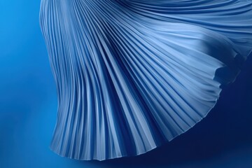 Leinwandbilder - Flowing fabric drapes softly against a vibrant blue background, showcasing intricate pleats and textures in a mesmerizing composition