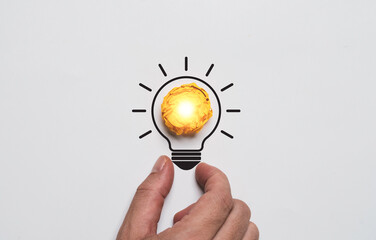 Fototapete - Yellow scrap paper inside of lightbulb drawing which it glowing on hand for creative thinking idea problem solving solution and innovation concept.