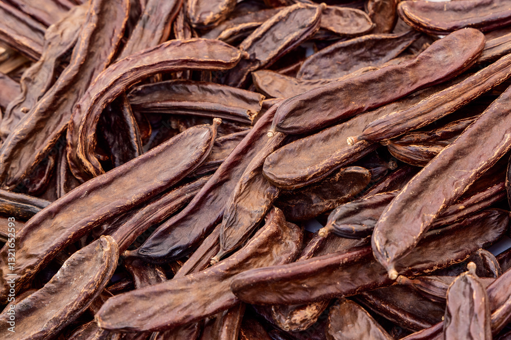Background of dried carob pods with wrinkled dark brown surfaces ...
