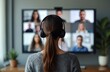 © miss irine - Woman in headphones at virtual meeting on screen with blurred participants during video conference. Online business discussion, remote work from home, modern workspace with latest tech.